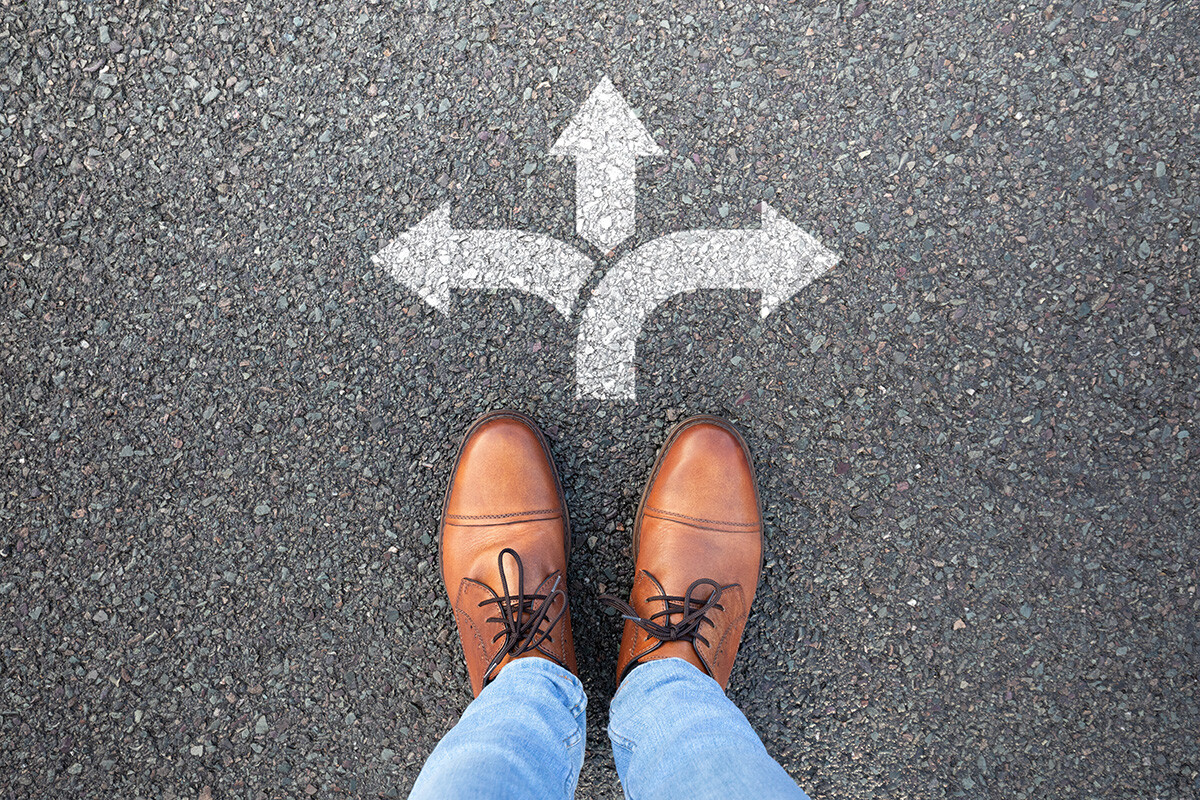 Person standing at arrows pointing different directions