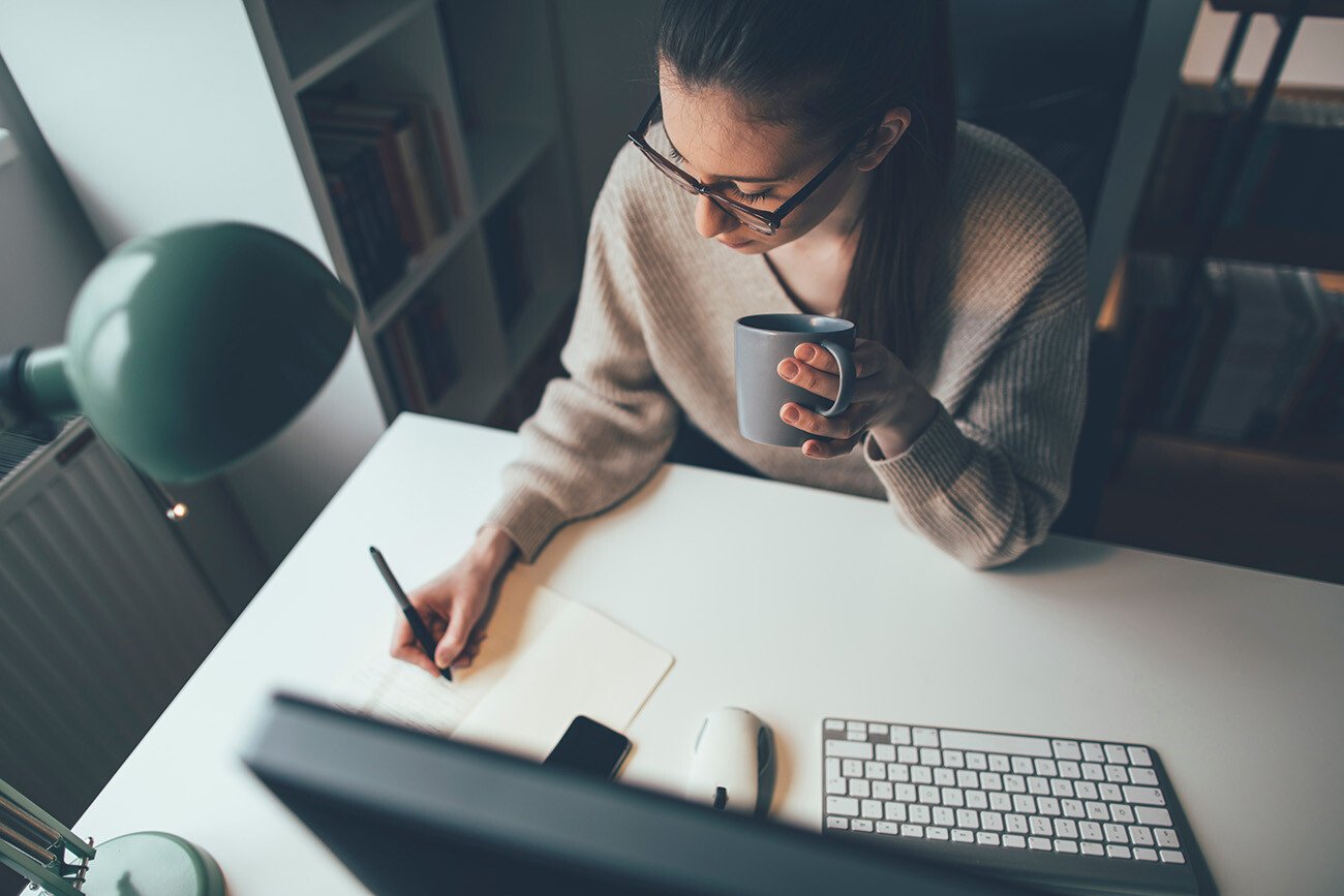 woman working at computer and taking notes