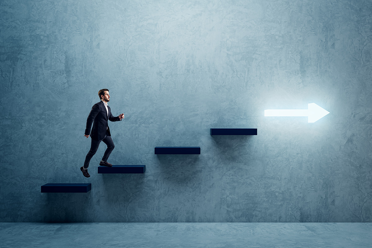 Businessman walking up steps toward illuminated arrow