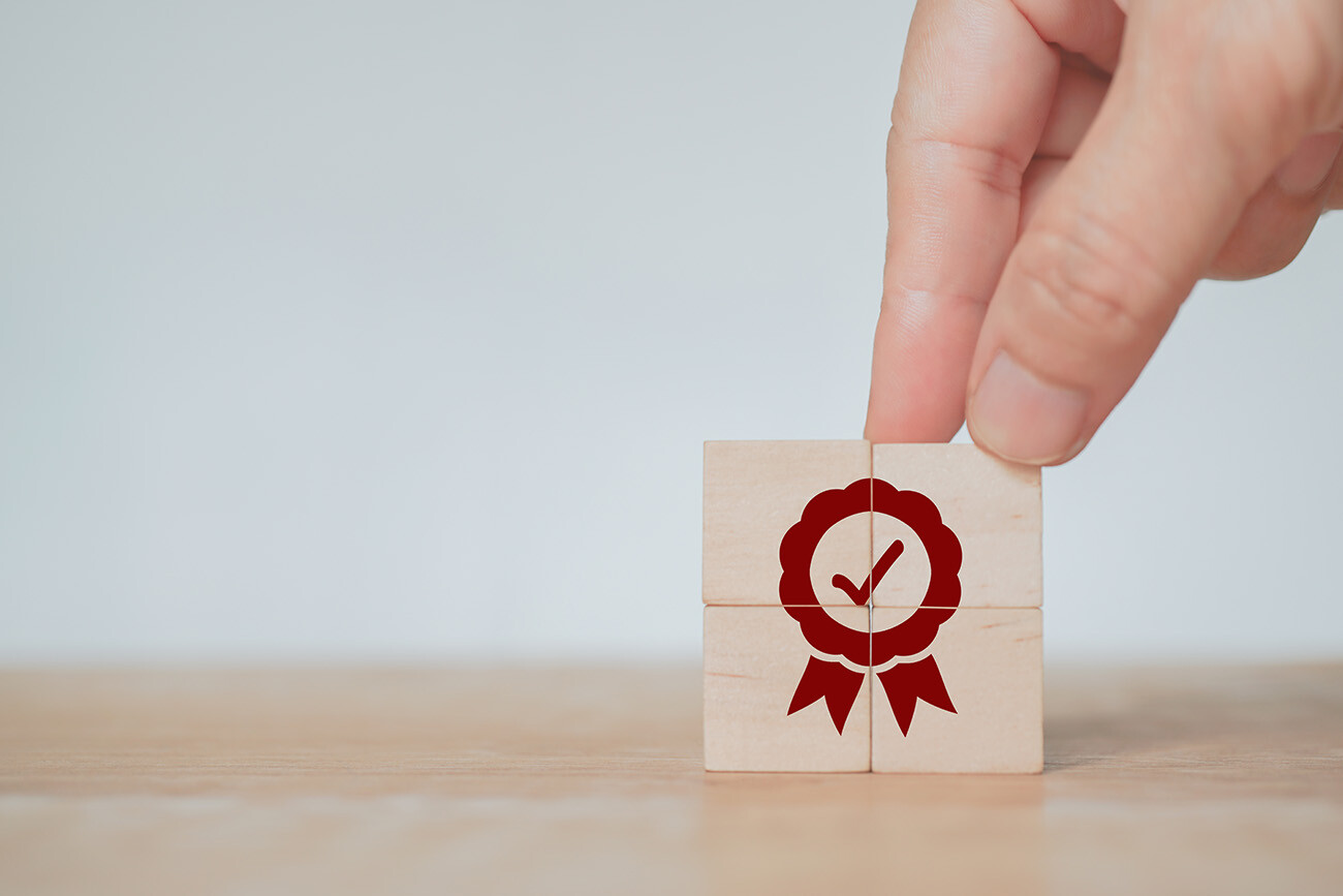 fingers holding wood blocks with an award ribbon and check mark