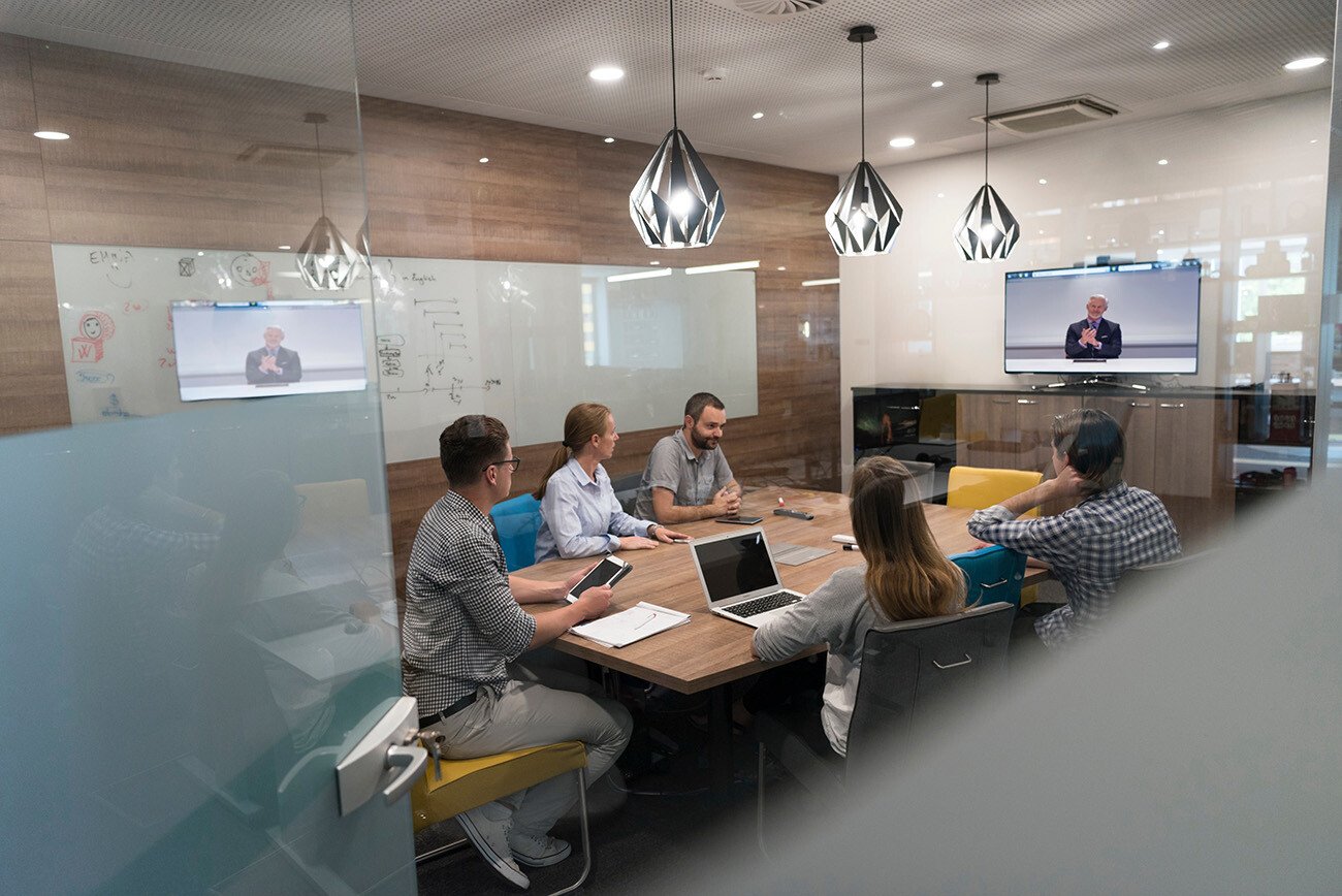 meeting in conference room with person remotely on TV